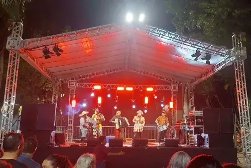 Palco coberto com estrutura de treliça, iluminação vermelha e caixas de som