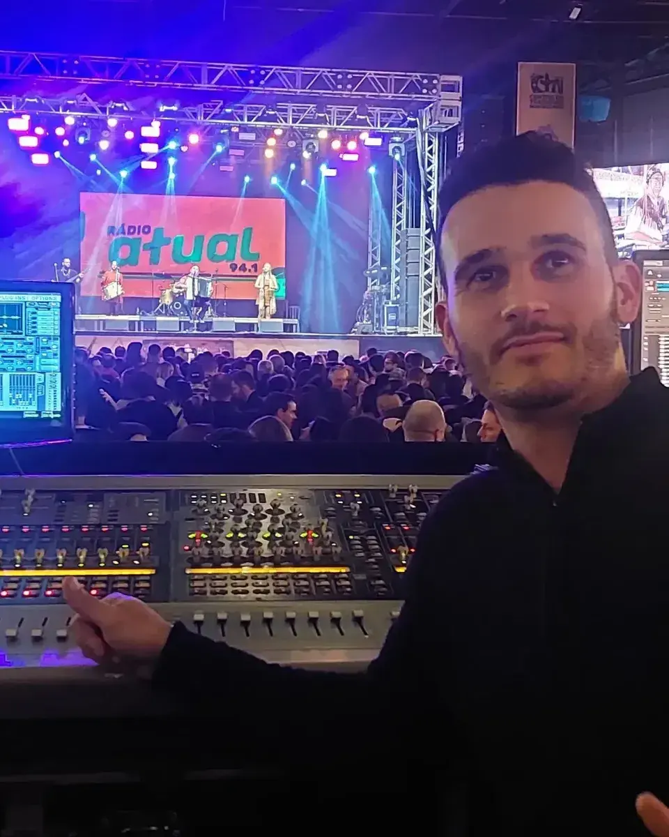 Técnico da A11 Eventos na mesa de som durante um show, com o palco iluminado ao fundo